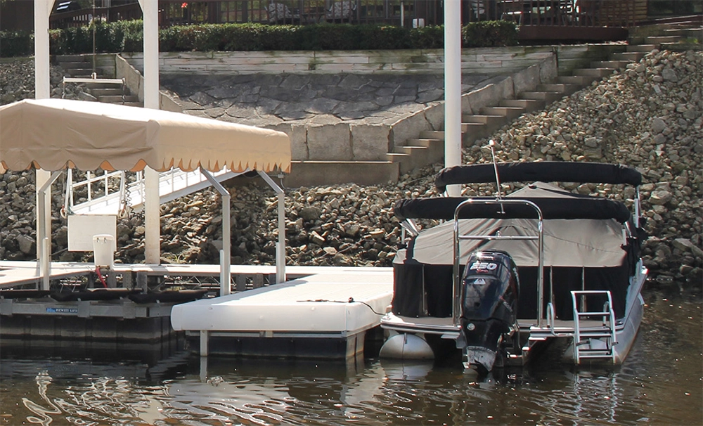 hewitt-boat-lift-dockstop-airdrie A covered pontoon boat docked at a Hewitt boat lift with a floating dock, installed by Dockstop in Airdrie, Alberta, Canada