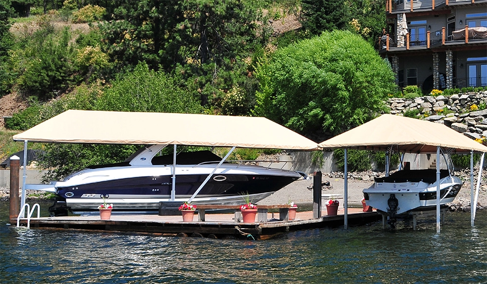 hewitt-dock-lift-airdrie-canada Two boats on Hewitt boat lifts with beige canopy covers, docked at a waterfront property, available at Dockstop in Airdrie, Alberta, Canada.